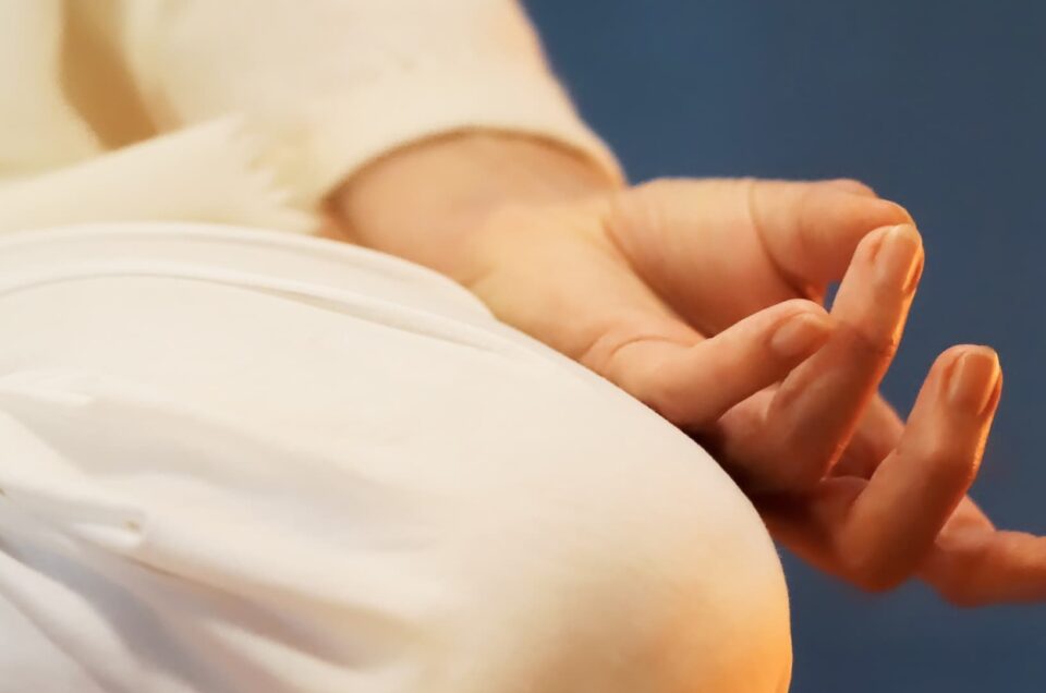 Yoga Position im Schneidersitz mit Hand, die eine Yoga Geste zeigt