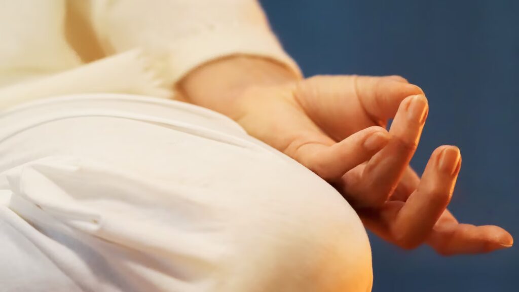 Yoga Position im Schneidersitz mit Hand, die eine Yoga Geste zeigt