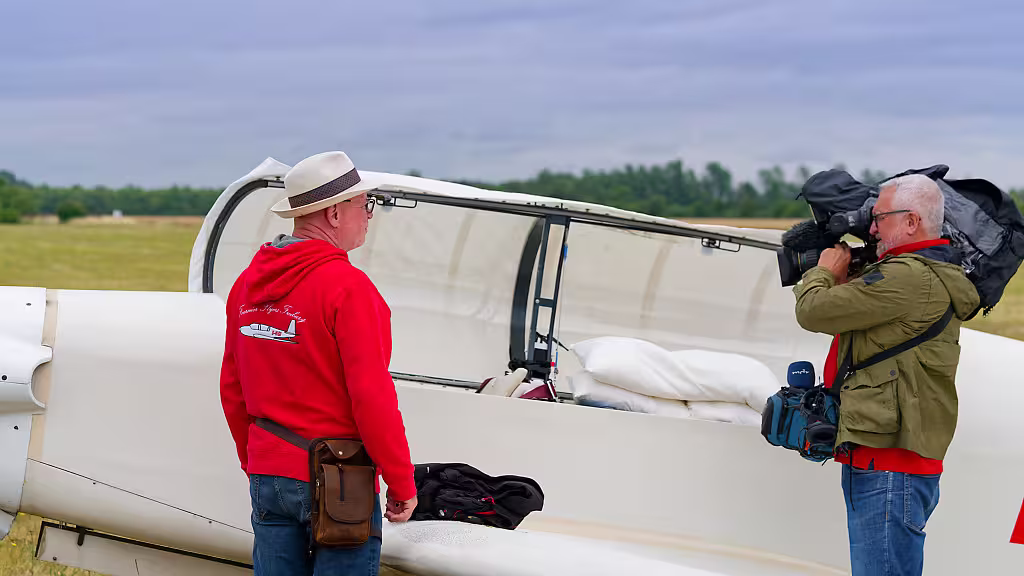 Pilot wird vor seiner Maschine vom Kameramann gefilmt